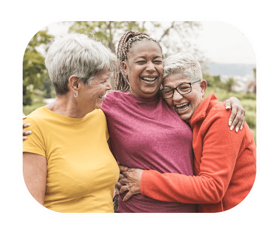 mature women embracing and smiling with hearing aids